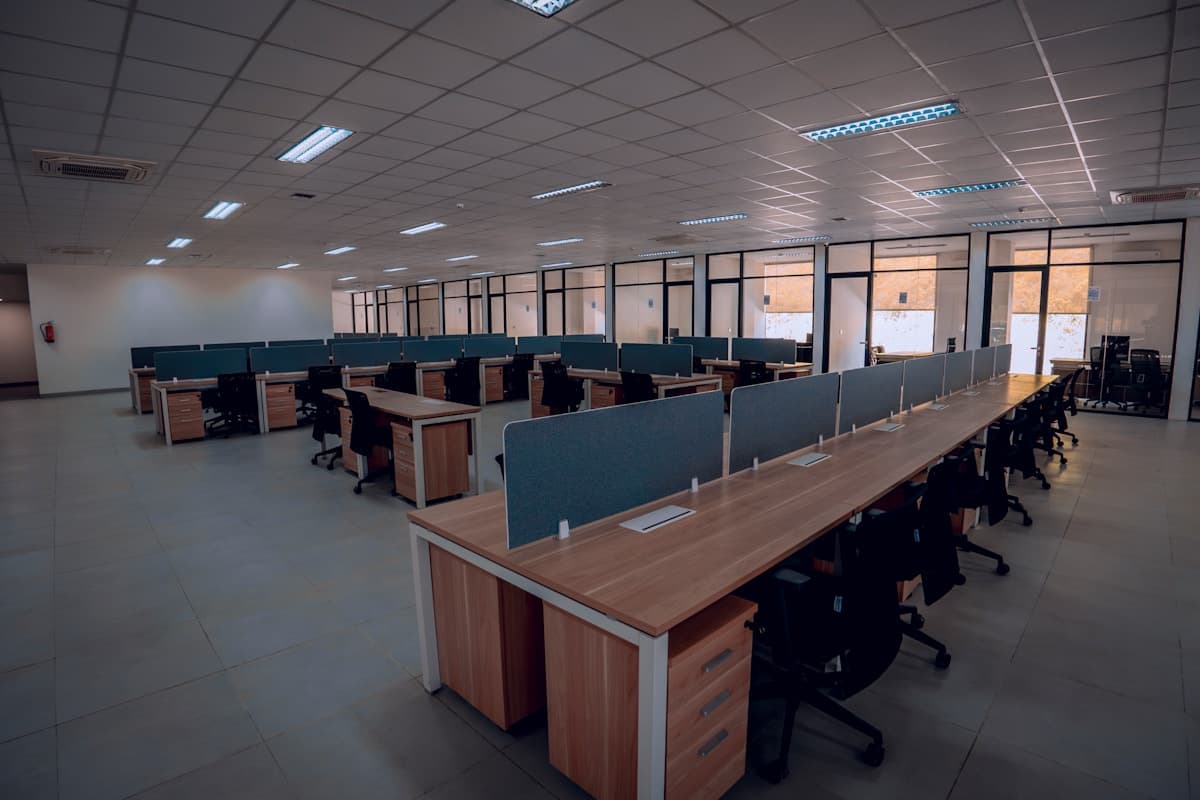 An open-plan office with rows of empty desks and chairs.
