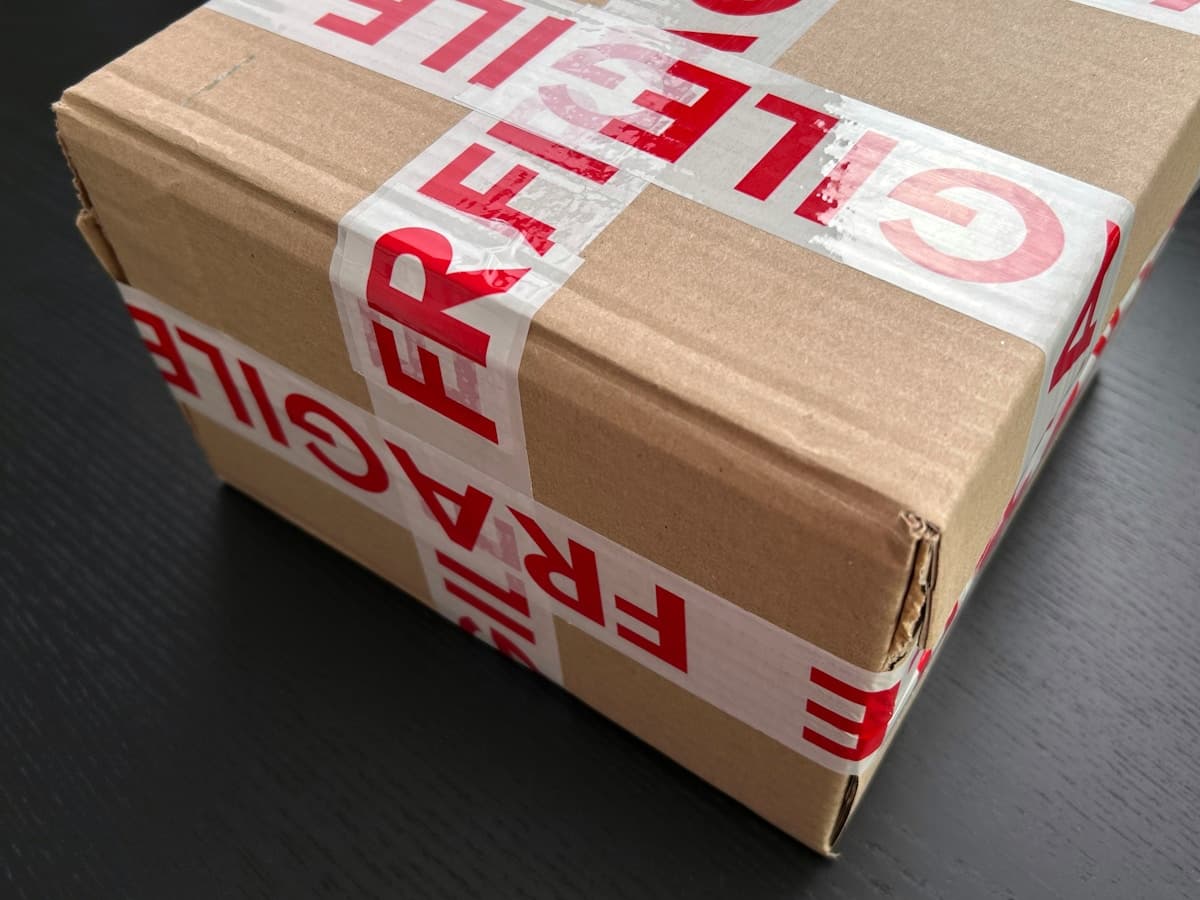 A cardboard carton sealed with red and white FRAGILE tape.