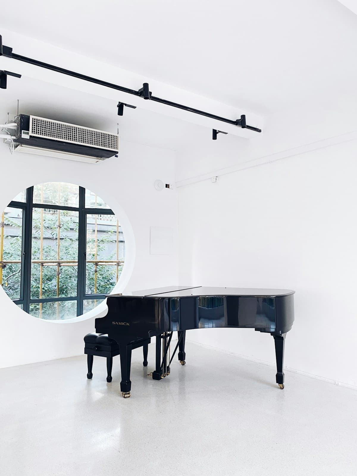 A black grand piano standing in a bright, otherwise empty room.
