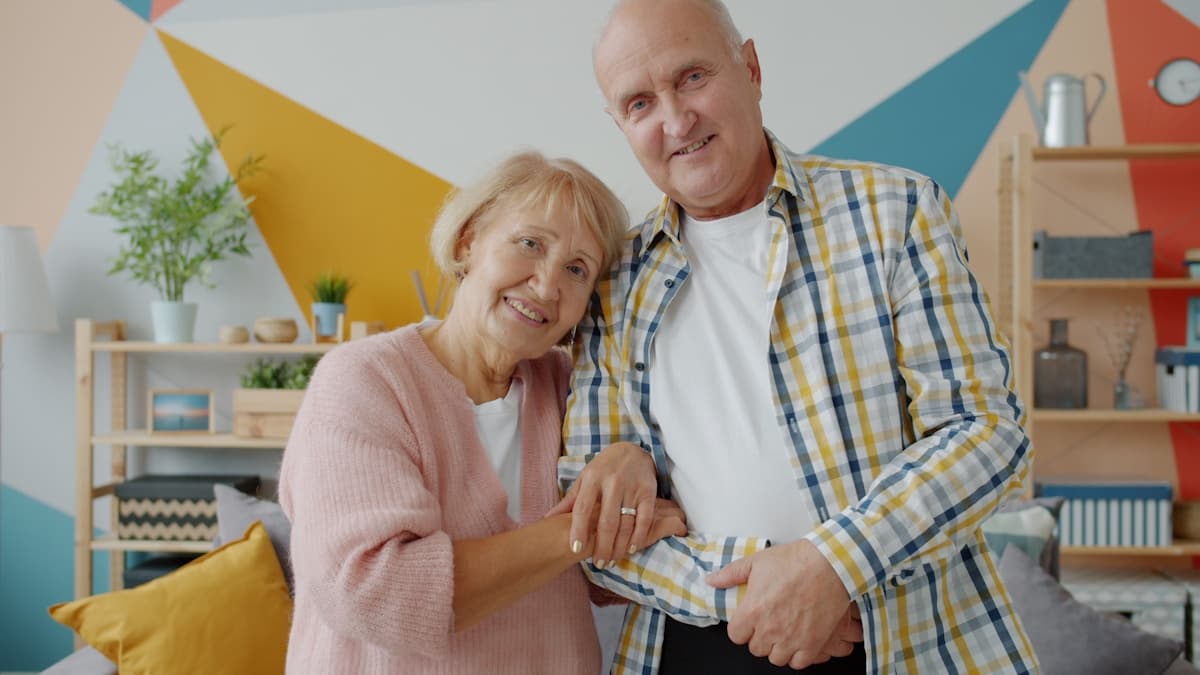 An older couple standing together and smiling at home.
