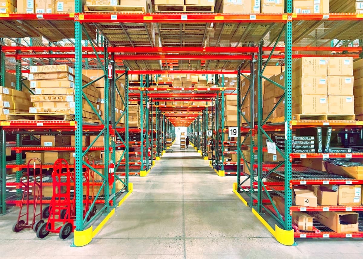 An aisle of tall warehouse racking stacked with palletised cartons.