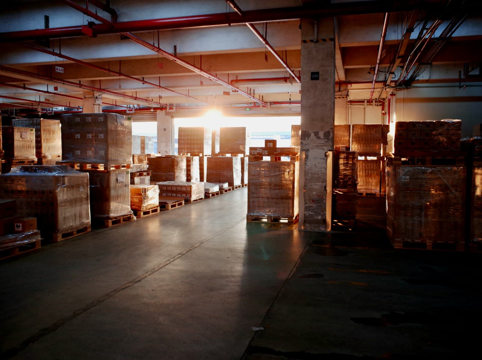 The inside of a warehouse with palletised goods stacked in rows.